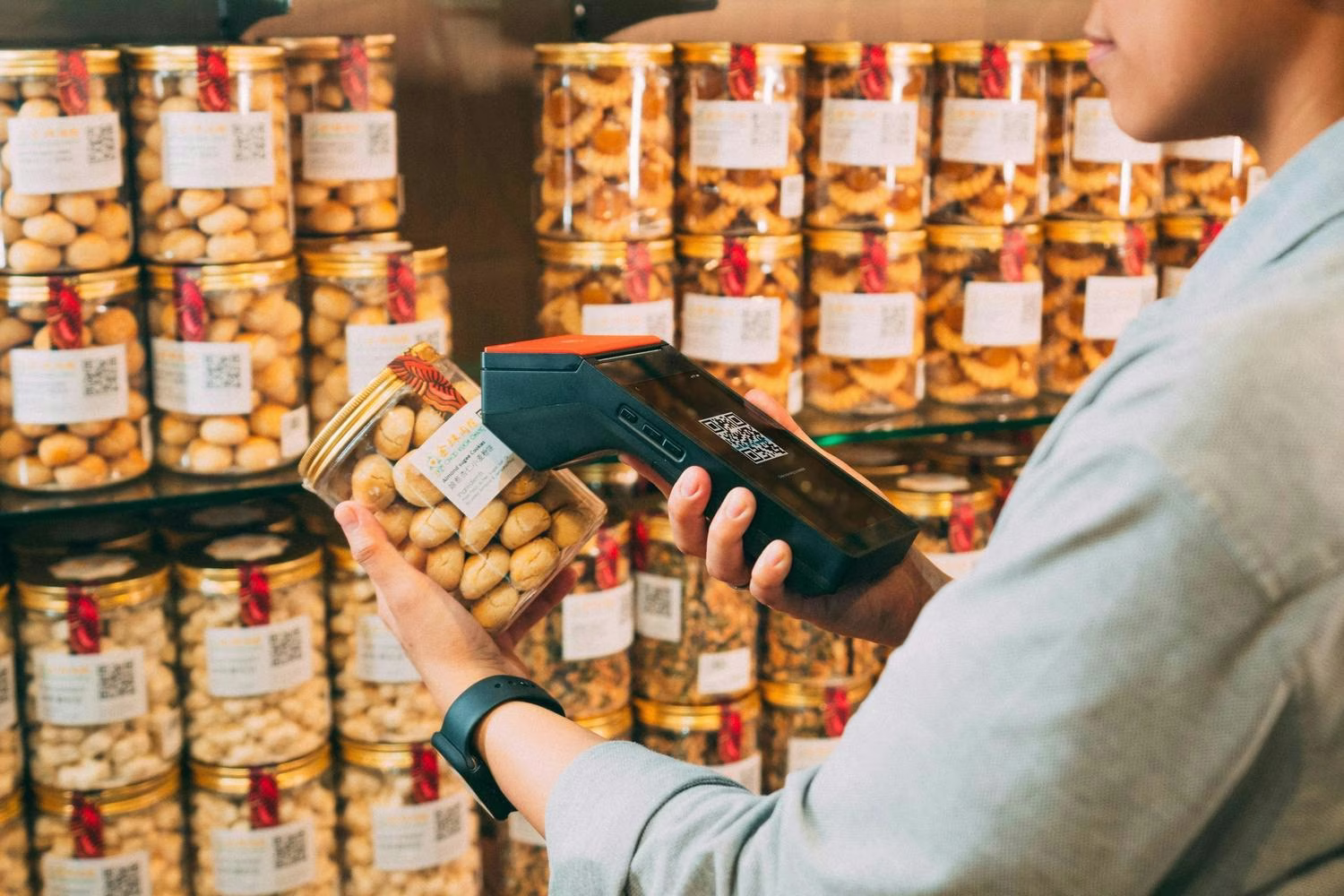 Person Scanning QR Code on Jar of Pickled Olives